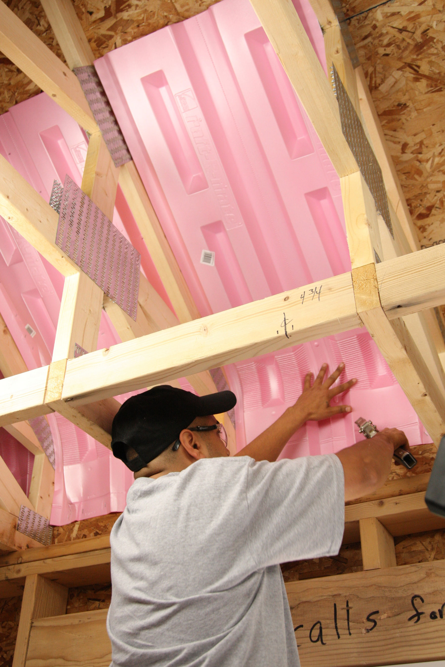 man installing pink baffles in new construction